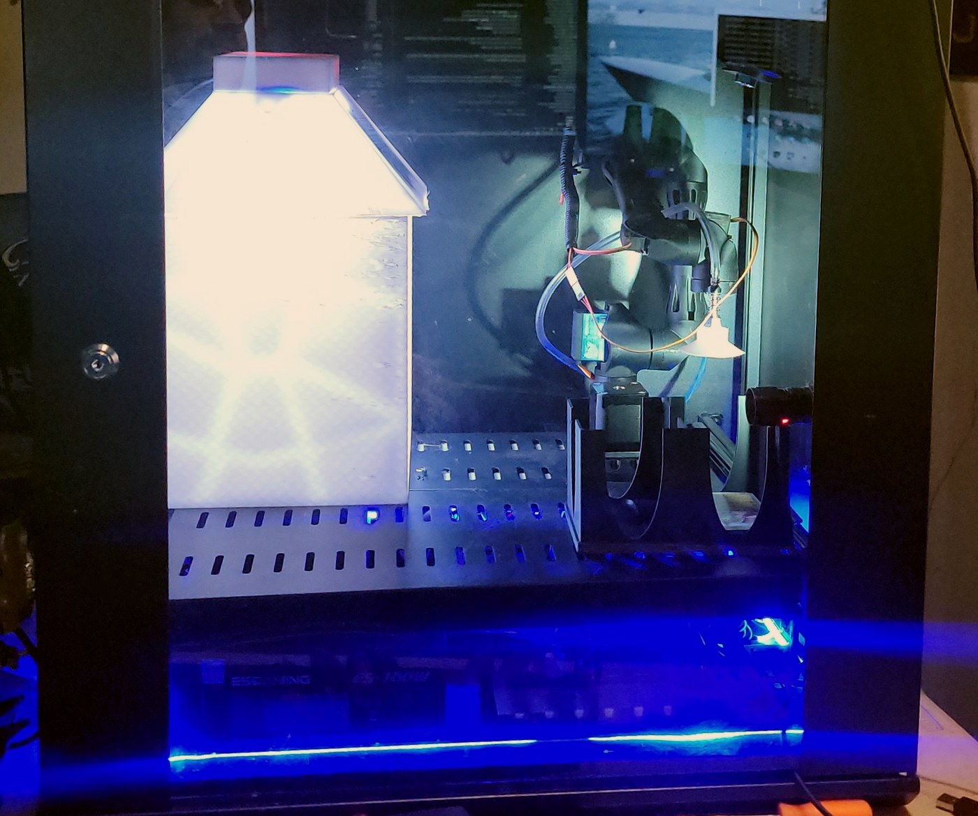 A NEXUS unit with the cabinet door closed: the controlled-light chamber glowing at left, the transfer arm and its vacuum pickup at right, over a slotted deck.
